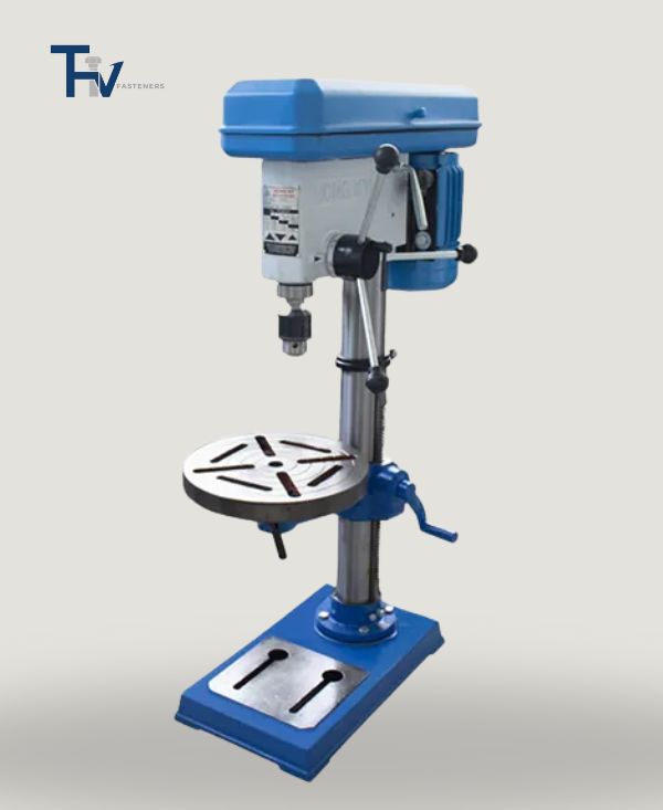A blue and white benchtop drill press from THV Fasteners' quality control lab, used for preparing samples or testing material penetration.